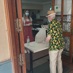 Persona mayor recoge bolsa de alimentos en el comer social de UDP Cádiz