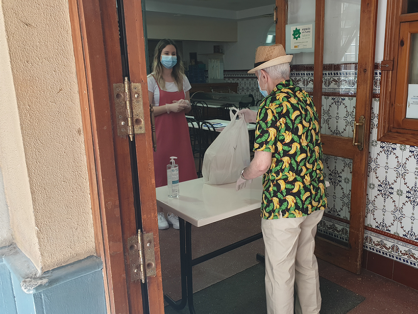 Persona mayor recoge bolsa de alimentos en el comer social de UDP Cádiz